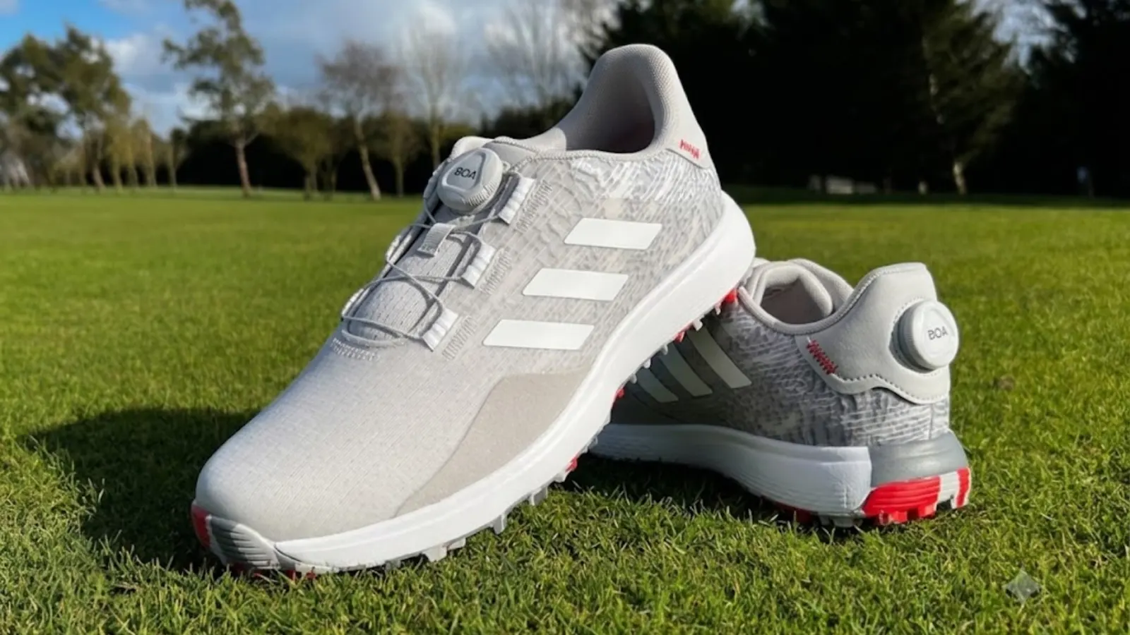 Grey Adidas EQT golf shoes on grass.